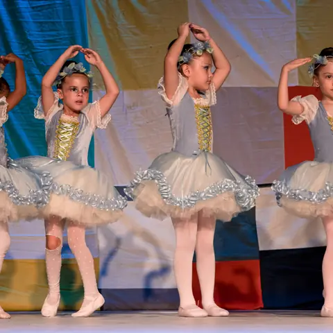 Bailarinas de tutu azul-claro com os braços em coroa.