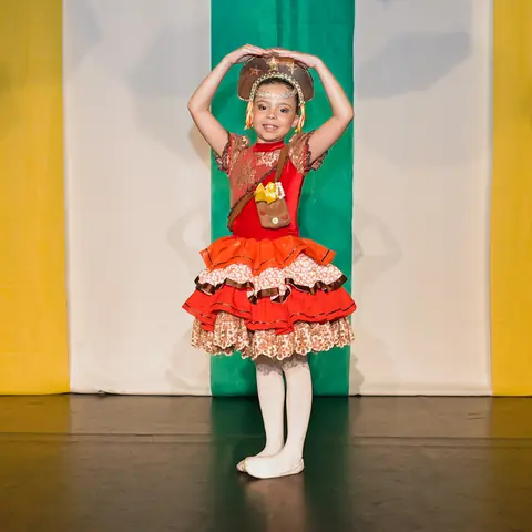 Bailarina de quadrilha com chapéu enfeitado e vestido vermelho.