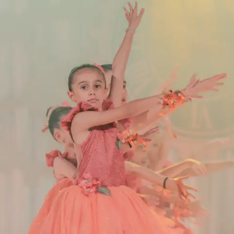 Bailarina de rosa-salmão com os braços para o alto.